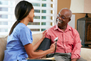 Nurse Visiting Senior Male Patient At Home - nursing taking resident blood pressure reading